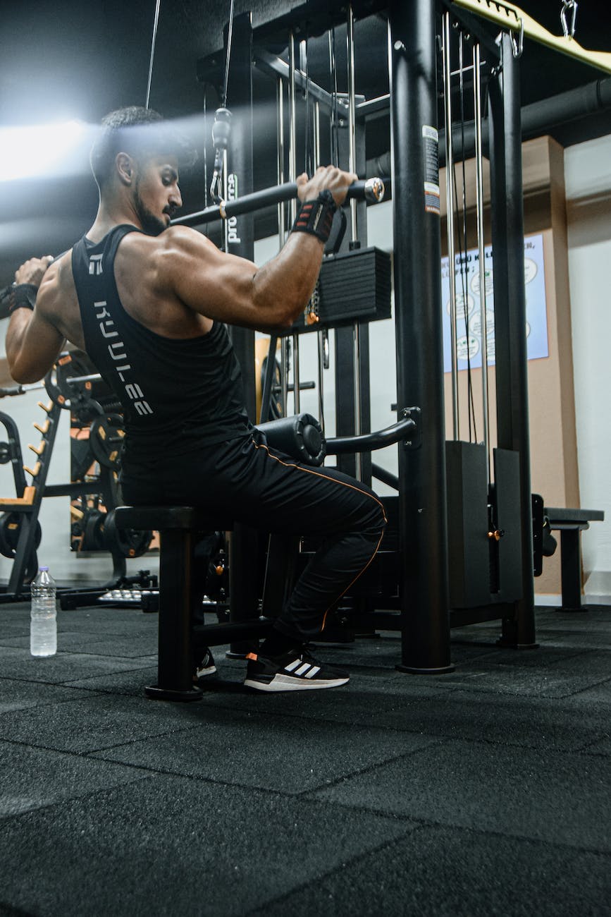 a muscular man using a lat pull down machine in a gym